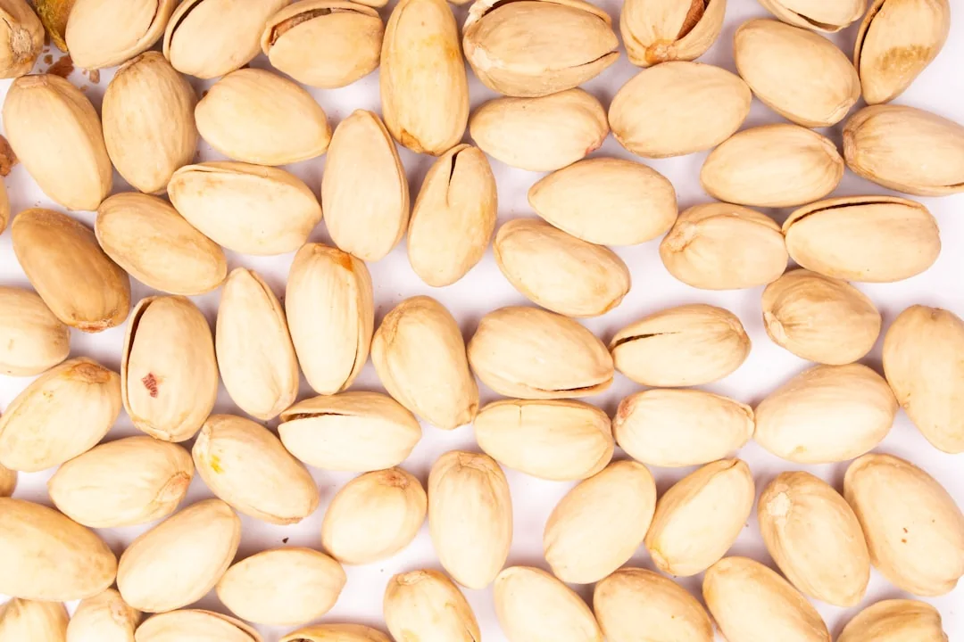 A pile of unshelled pistachios on a white background